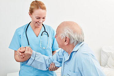 Pflegerin hält einem Patienten die Hand