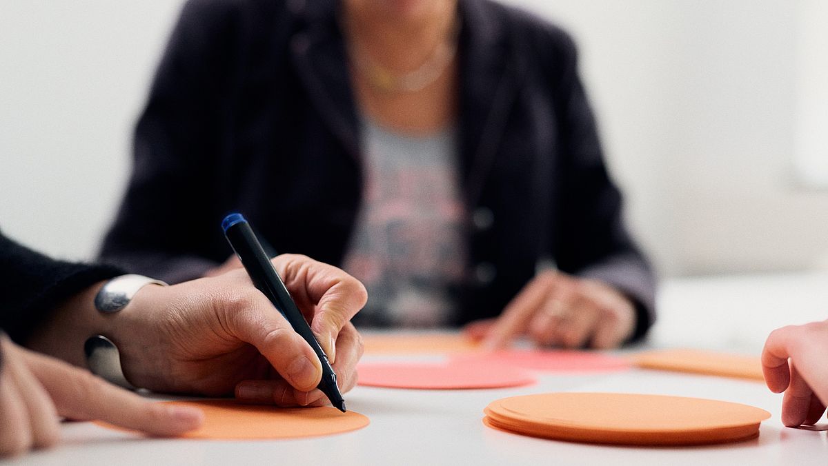 Menschen schreiben auf runde PostIts