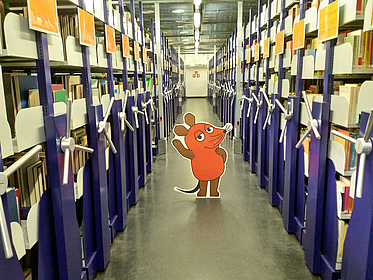 Maus steht im Büchermagazin
