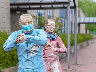 A statue with a face mask on the university boulevard.
