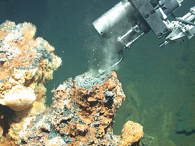 Aus einer Gesteinsformation ersteigt Fluid, welches von einem Tauchrobotor aufgenommen wird.