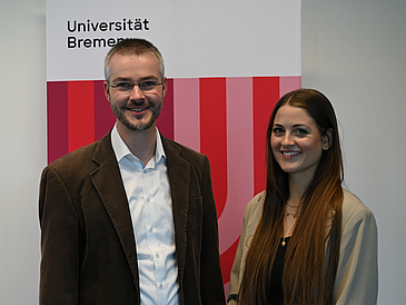 Prof. Paha und W. Siebert vor einem Banner der Universität Bremen