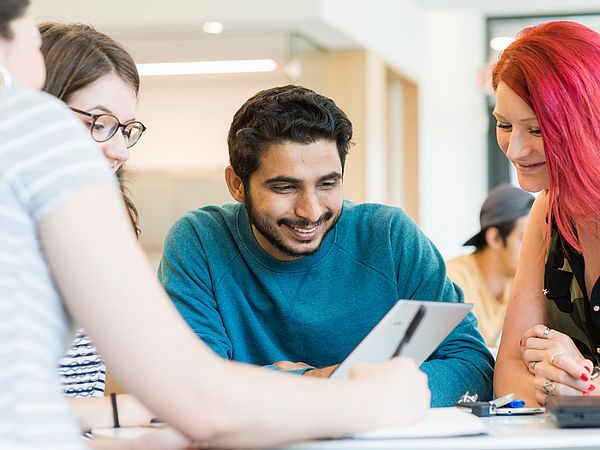 Vier Studierende arbeiten gemeinsam an einem Laptop.