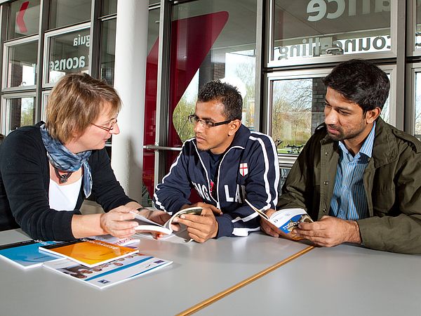 Three people in conversation about a flyer.