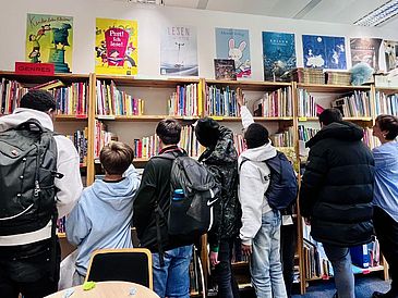 Die Jungs und Myriam Macé vorm Bücherregal der Bilderbuchbibliothek