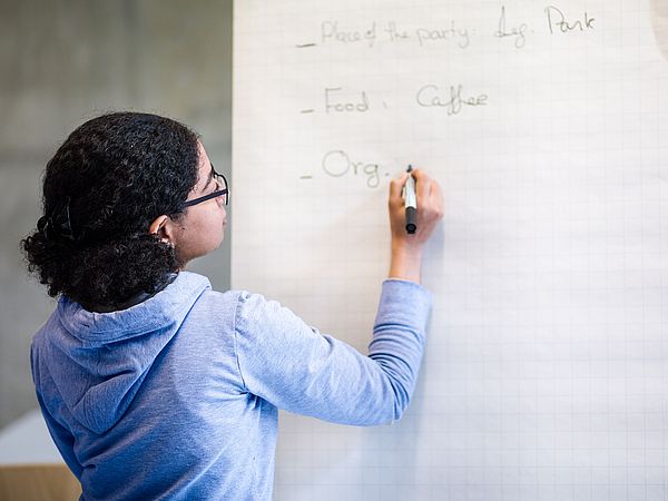 Eine Person schreibt auf ein Flipchart.