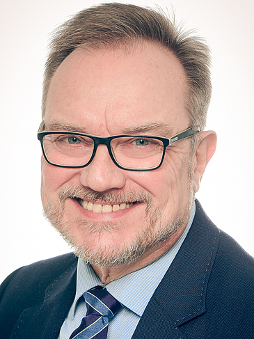 Foto von Herrn Professor Doktor Martin Missong, der sympathisch in die Kamera lächelt, bekleidet mit blauem Anzug und gestreifter Krawatte.