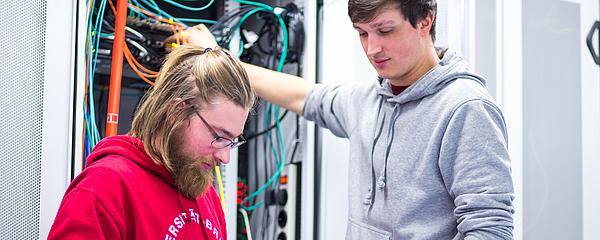 Zwei Personen arbeiten an einem Serverschrank.