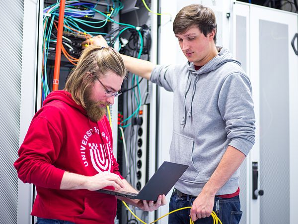 Two people are working on a server rack.