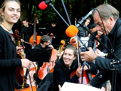 Orchester der Universität Bremen beim Aufbau mit Geigerin und Cellistin