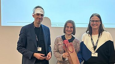 Personen stehen vor einer Präsentation und nehmen Preis entgegen