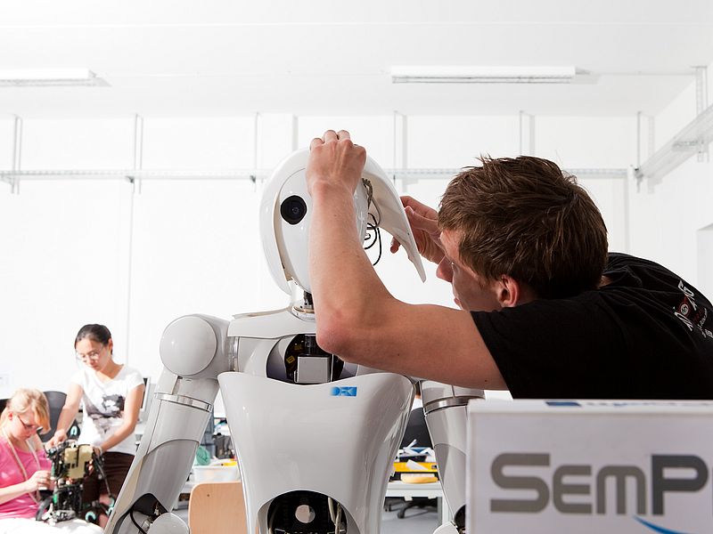 A person works on a humanoid robot.