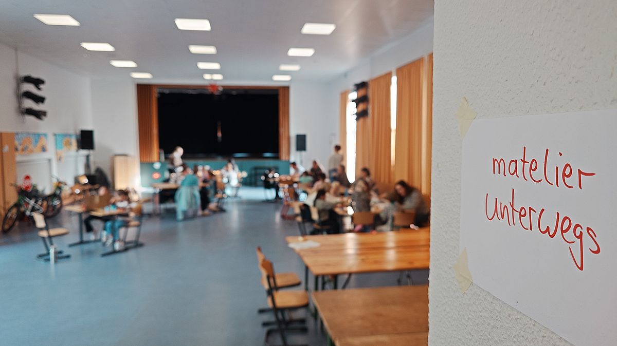 matelier unterwegs 2027 Ein großer Raum mit Gruppentischen, an denen Studierende und Kinder arbeiten.