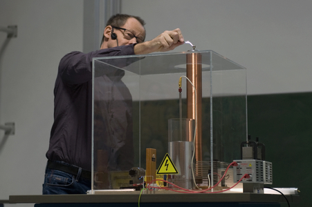 Blitzartiger Funkenüberschlag von Tesla-Spule auf metallischen Gegenstand in der Hand von Prof. Nothold
