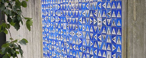 Mural made of hundreds of small blue tiles with traffic signs on them