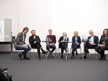 Foto des Podiums zum Thema “ Wie kann man nachhaltiges Forschen, Lehren, Lernen und Hochschulleben an den Hochschulen umsetzen?“ bei dem Vertreter*innen aus den Rektoraten, der Studierendenschaft, der Politik und dem Klimamanagement der Hochschulen anwesend waren, geleitet durch Jürgen Ritterhoff von Ecolo.