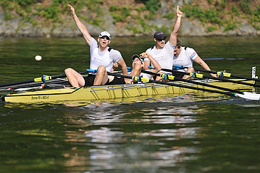 Vier Männer in Siegerpose auf Doppelvierer-Boot