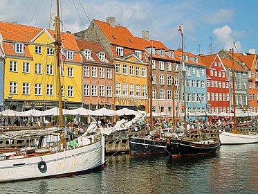 Mehrere bunte Häuser und Boote am historischen Hafenkanal im Zentrum von Kopenhagen.