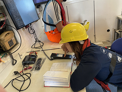 Frau auf einem Forschungsschiff macht eine Ansage über die Funksprechanlage