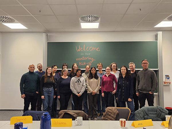 A group photo of the mentoring team standing in front of a blackboard