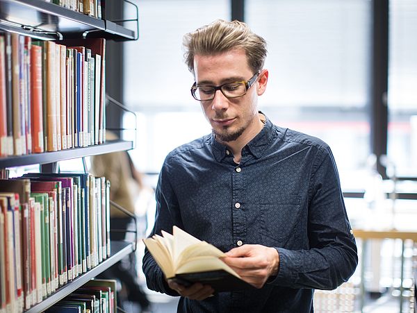 Ein Besucher der Bibliothek blättert in einem Buch.