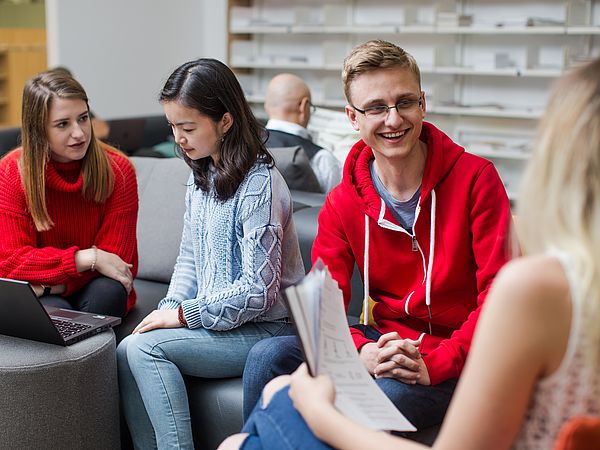 Students work with a laptop and documents.