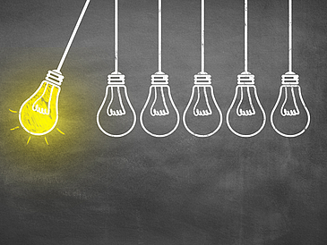 Vor einer schwarzen Tafel sieht man wie mit Kreide gezeichnete Glühbirnen, die auf derselben Höhe herunter hängen. Sie sind wie ein Kugelstoßpendel angeordnet: links holt eine gelb leuchtende Glühbirne aus, die anderen fünf hängen ohne Leuchteffekt rechts daneben.