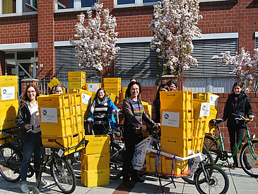 Frauen mit Fahrrädern, auf denen Postkisten stehen