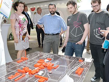 Three men and a woman looking at a 3D model of University buildings.