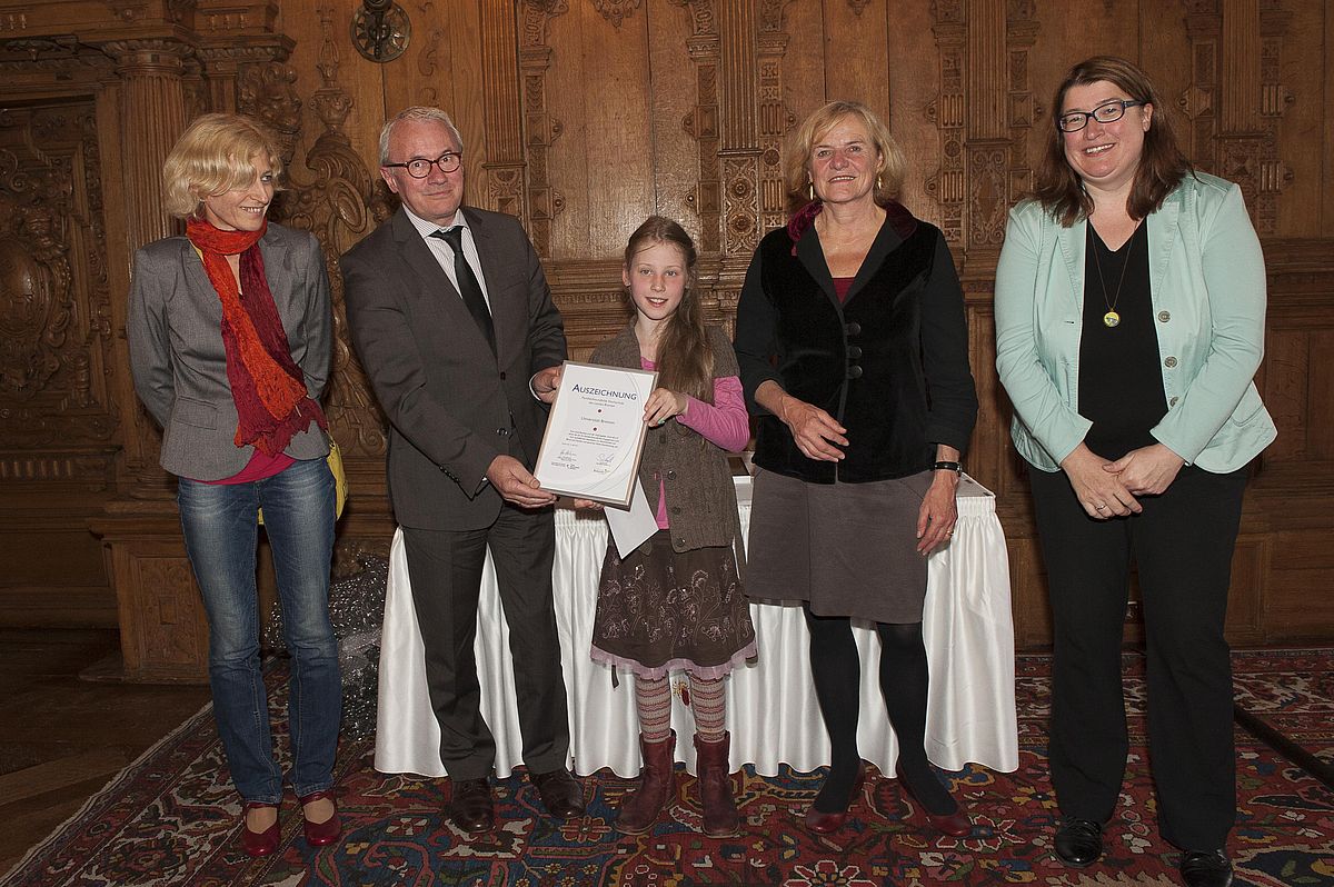 Vier Erwachsene, ein Kind in der Mitte mit Auszeichnung