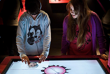 Zwei Jugendliche testen einen Multimediatisch.