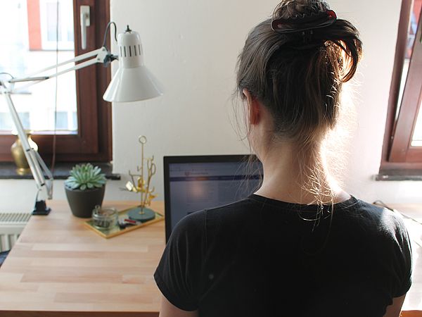 Eine Person arbeitet zuhause an ihrem Laptop.