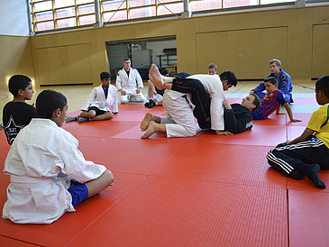 Judokämpfer sitzen in Turnhalle.
