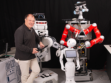 Professor Michael Beetz und drei Roboter