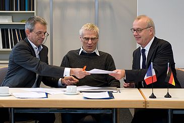 Drei Männer unterschreiben einen Vertrag