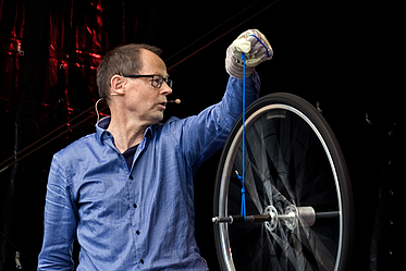 Mann hält sich drehendes Rad hoch