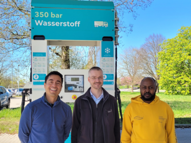 Julian Wilches, Prof. Johannes Paha und Alex Kimani vor einer Wasserstofftankstelle