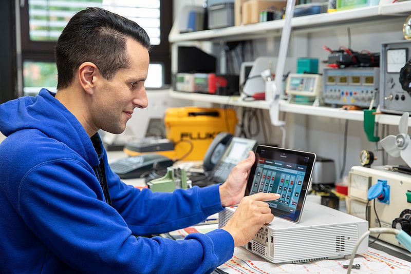 One person operates a tablet.