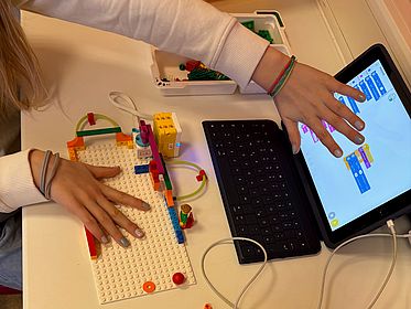 Ein Laptop, davor Hände mit Legosteinen