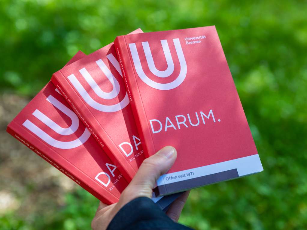 One hand holds three magazines, on the cover you can read the word DARUM