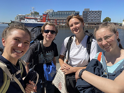 Vier Personen vor einem Forschungsschiff