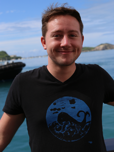 Foto von Christian Hansen mit schwarzem T-Shirt mit blauem Walfischmotiv an Bord der Sonneexpedition 253