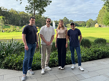 Vier Personen stehen vor einer Wiese