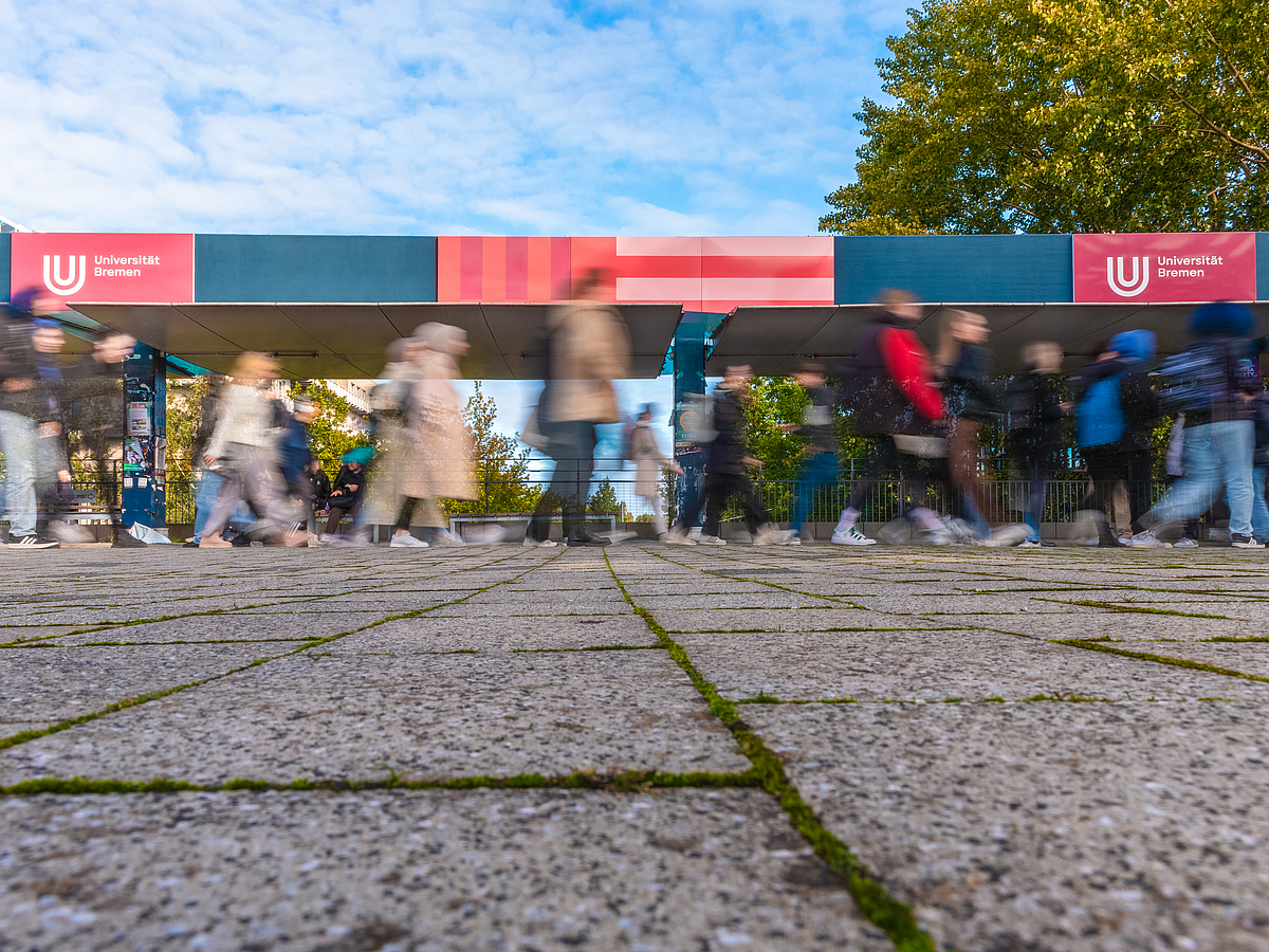 People blurred by their movement, walking across the boulevard