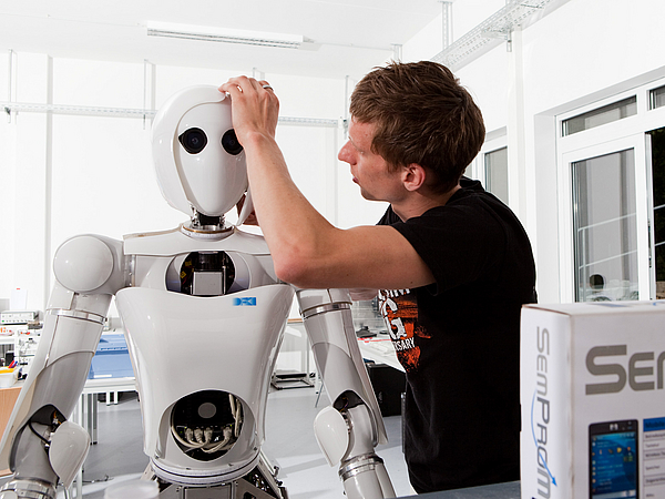 A person works on a humanoid robot.