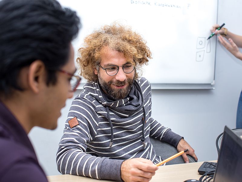 Zwei Männer arbeiten am Laptop.