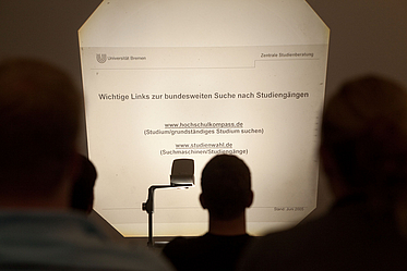 Menschen schauen auf eine Projektorfolie.