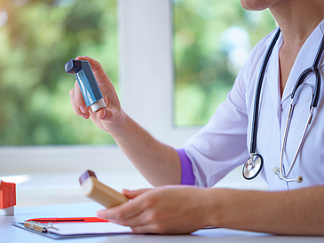 Arzt hält im Patientengespräch Asthmasprays in der Hand