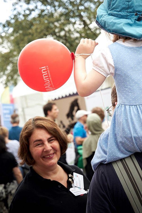 AUfnahme vom Open Campus 2024. Mauela lächelt einem Kind zu das auf der Schulter eines Erwachsenes sitzt
