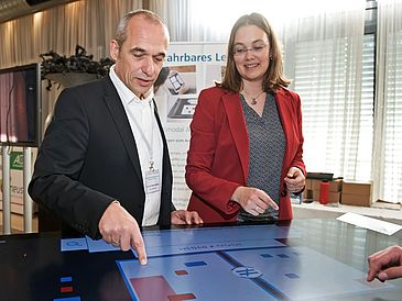 Man and woman standing at digital table.
